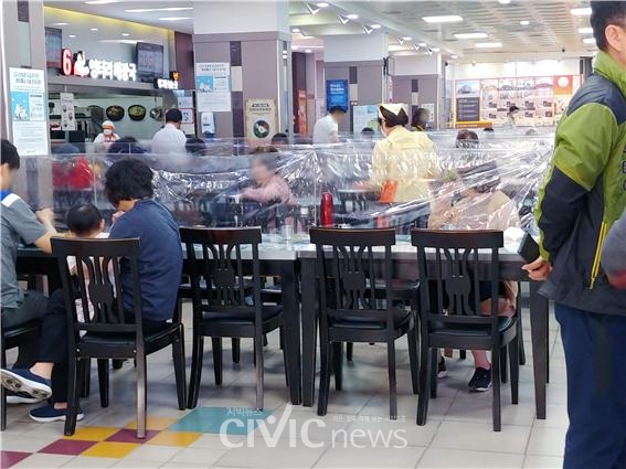 여행객들이 고속도로 휴게소에서 비닐 칸막이가 쳐진 식탁에서 점심 식사를 하고 있다(사진: 취재기자 안시현).