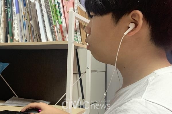 중학생 강윤우 군이 집에서 이어폰을 귀에 꽂고 화상강의를 듣고 있다(사진: 취재기자 강여진).