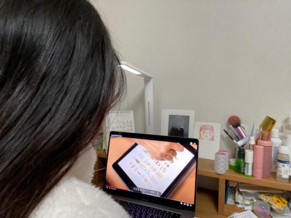 한 여자가 노트북으로 고등학생 때 올렸던 일상 영상을 21살이 된 후 다시 시청하고 있다 (사진: 취재기자 김지우).
