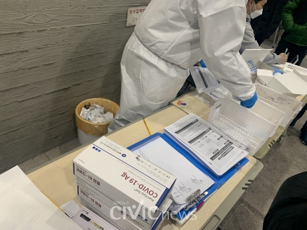 보건소 직원과 의료진이 코로나19 검사신청서와 신분증을 대조한 후 신속항원검사 키트를 나눠주고 있다(사진: 취재기자 권지영).