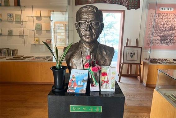 향파 이주홍 선생의 얼굴을 본떠 만든 동상 앞에 그를 기리는 꽃들과 그의 대표 작품 중 하나인 ‘이순신 장군’이 놓여있다(사진: 취재기자 조우진).