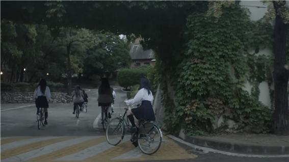 유튜브 뉴진스 ‘Ditto’ 뮤직비디오에 올라온 영상으로 청라언덕을 배경으로 자전거를 타고 가고 있다(사진: 유튜브 HYBE LABELS 캡처).